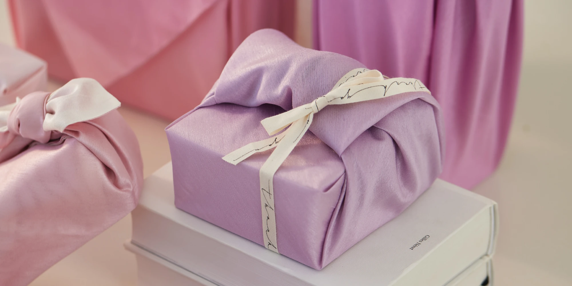 A beautifully wrapped gift in light pink color placed on top of a book